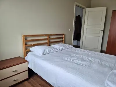 a bedroom with a white bed with a wooden headboard at Apartments in old town Latako Street in Vilnius