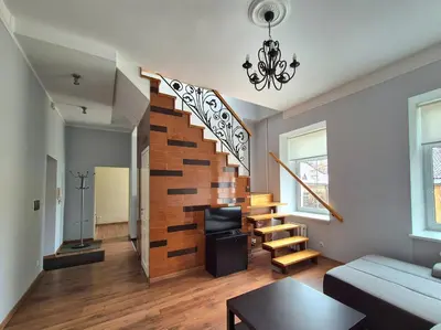 a living room with a wooden staircase with a chandelier at Apartments in old town Latako Street in Vilnius