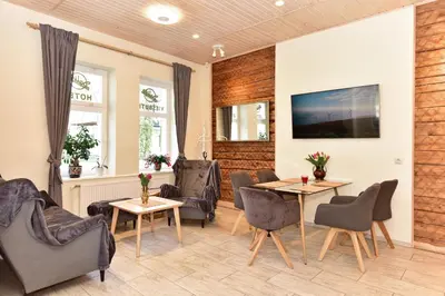 a living room with chairs and tables and a tv at Dalija in Druskininkai