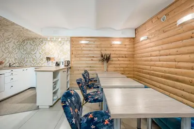 a kitchen with wooden walls and tables and chairs at HOME Apart-Hotel Vilnius in Vilnius