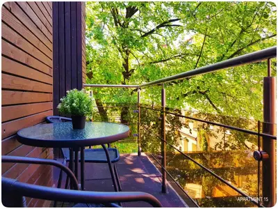 a small table on a balcony with a tree at HOME Apart-Hotel Vilnius in Vilnius