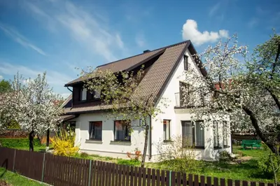 a white house with a black roof and a fence at Dina Apartments in Druskininkai