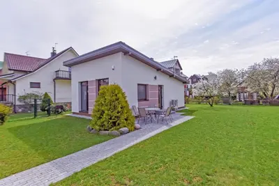 a white house with a table and chairs in a yard at Birutes House in Druskininkai
