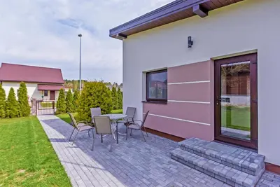 a patio with a table and chairs next to a house at Birutes House in Druskininkai