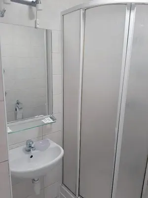 a white bathroom with a sink and a shower at Kambarių nuoma - Šiauliai SAURIDA in Šiauliai