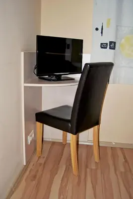 a black chair sitting in front of a desk with a television at Kambarių nuoma - Šiauliai SAURIDA in Šiauliai