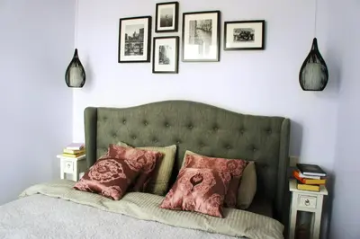 a bedroom with a bed with pink pillows and framed pictures at Mono Ray Apartments in Druskininkai