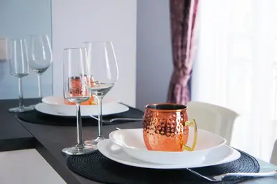 a table with wine glasses and a cup on it at Mono Ray Apartments in Druskininkai