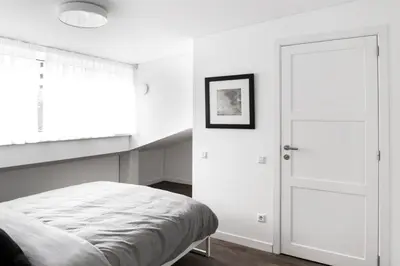 a white bedroom with a bed and a door at Deluxe Apartments by Hostlovers in Kaunas