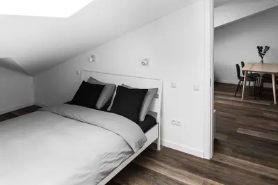 a white bedroom with a bed and a table at Deluxe Apartments by Hostlovers in Kaunas