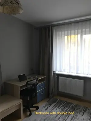 a bedroom with a desk and a window with a laptop at Roman in Druskininkai
