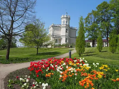 a garden of flowers in front of a white building at Roman in Druskininkai