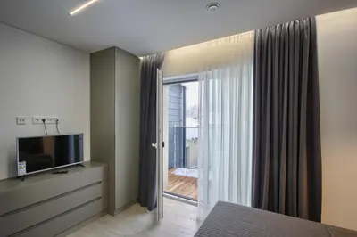 a bedroom with a sliding glass door to a balcony at Nikolas Apartamentai - Birstono 7 in Druskininkai