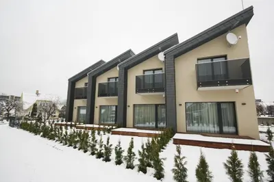 a building with a row of trees in the snow at Nikolas Apartamentai - Birstono 7 in Druskininkai