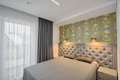 a bedroom with a bed and a wall with yellow flowers at Nikolas Apartamentai - Birstono 7 in Druskininkai