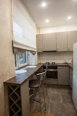 a kitchen with white cabinets and a counter with chairs at Mickeviciaus str apartment in Kaunas