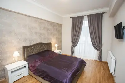 a bedroom with a bed and two night stands and two windows at Mickeviciaus str apartment in Kaunas