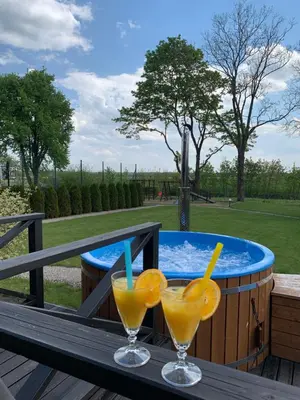 two glasses of orange juice on a table next to a hot tub at Graikinė in Kėdainiai