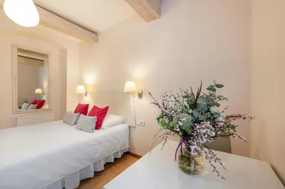 a bedroom with a bed and a vase of flowers on a table at Guoda Apartments in Vilnius