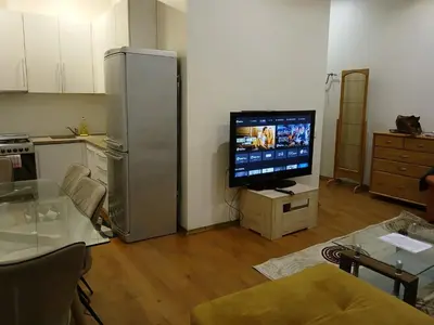 a living room with a flat screen tv and a kitchen at Donelaičio 42 in Kaunas