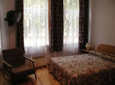 a bedroom with a bed and a chair and windows at Parko Vila in Druskininkai