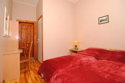 a bedroom with a red bed and a wooden floor at Parko Vila in Druskininkai