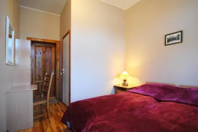 a bedroom with a red bed and a table with a lamp at Parko Vila in Druskininkai