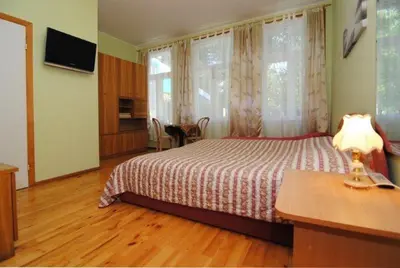a bedroom with a bed and a table with a lamp at Parko Vila in Druskininkai