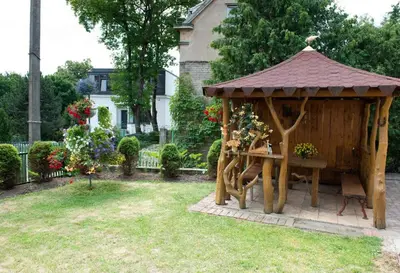 a wooden gazebo with a table in a yard at Petro delux apartments in Kaunas