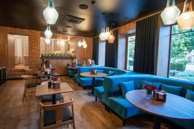 a restaurant with blue chairs and tables and people in the background at Hotel Tomas in Šiauliai