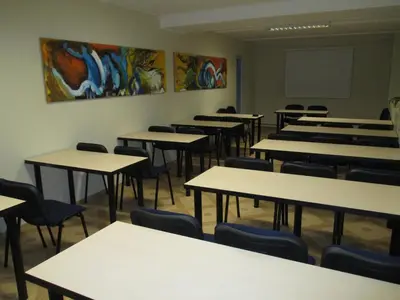 an empty classroom with tables and chairs and a chalkboard at Hotel Tomas in Šiauliai