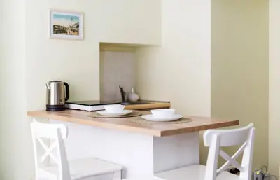a kitchen with a counter with two white stools at Cozy Apt in the Heart of Old Town in Vilnius