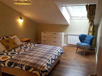 a bedroom with a bed and a blue chair at City Dawn Gate Apartment in Vilnius