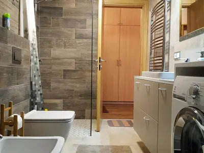 a bathroom with a toilet and a washer and dryer at City Dawn Gate Apartment in Vilnius