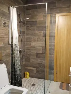 a bathroom with a shower with a glass door at City Dawn Gate Apartment in Vilnius