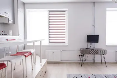 a white kitchen with white tables and chairs and a television at Sandra apartamentai in Kaunas