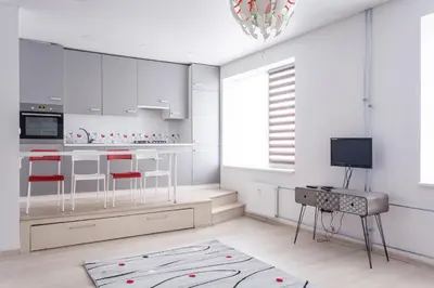 a kitchen with white cabinets and red chairs and a television at Sandra apartamentai in Kaunas