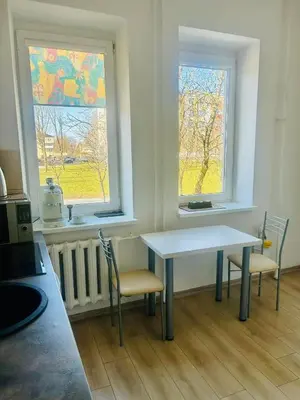 a kitchen with a table and two chairs and two windows at Ezero apartamentai in Šiauliai