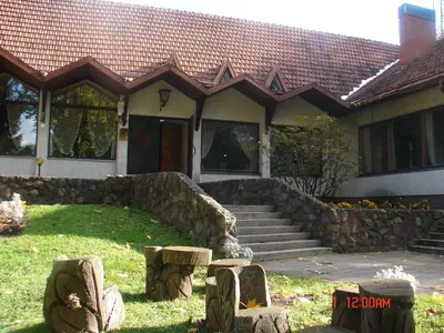 a house with a stone wall in front of it at Senieji Bačkonys in Bačkonys