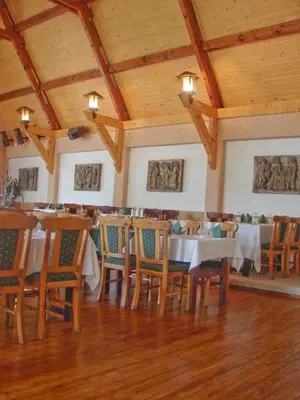 a dining room with tables and chairs and wooden ceilings at Senieji Bačkonys in Bačkonys