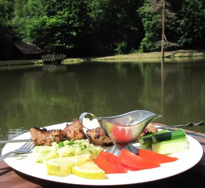 a plate of food on a table near a body of water at Senieji Bačkonys in Bačkonys