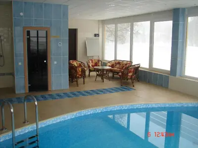 a swimming pool with chairs and a table next to a tablektop at Senieji Bačkonys in Bačkonys