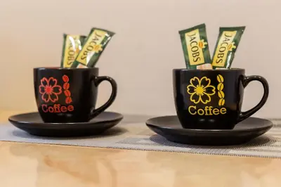 two black coffee cups with currency in them on plates at Pigi nakvyne in Šiauliai