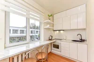a kitchen with white cabinets and a large window at Apartamentai Druskininku centre in Druskininkai