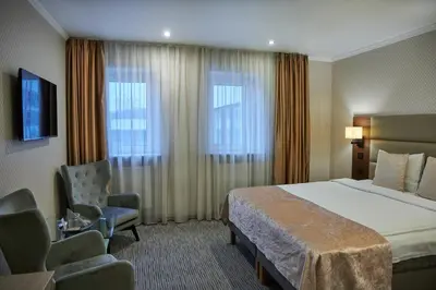 a hotel room with a bed and a chair at Olympus Hotel in Kaunas