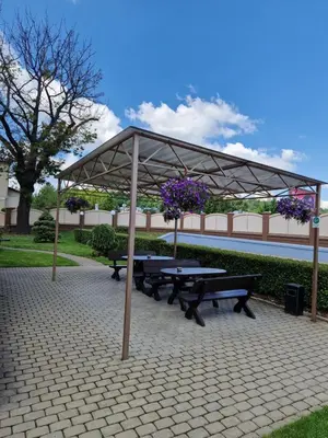 a picnic shelter with two benches and purple flowers at Olympus Hotel in Kaunas