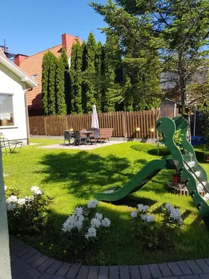 a garden with a green snake statue in the grass at Zveryno guest house in Vilnius