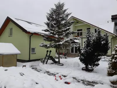 a house with a christmas tree in the snow at Zveryno guest house in Vilnius