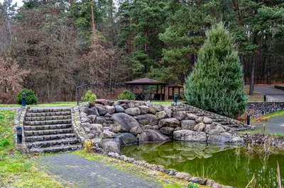 a garden with a pond and rocks and a gazebo at Park Villa Hotel in Vilnius