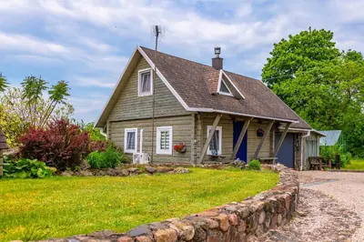 a small house with a stone wall in front of it at Vila Terra Resort in Girsteitiškis